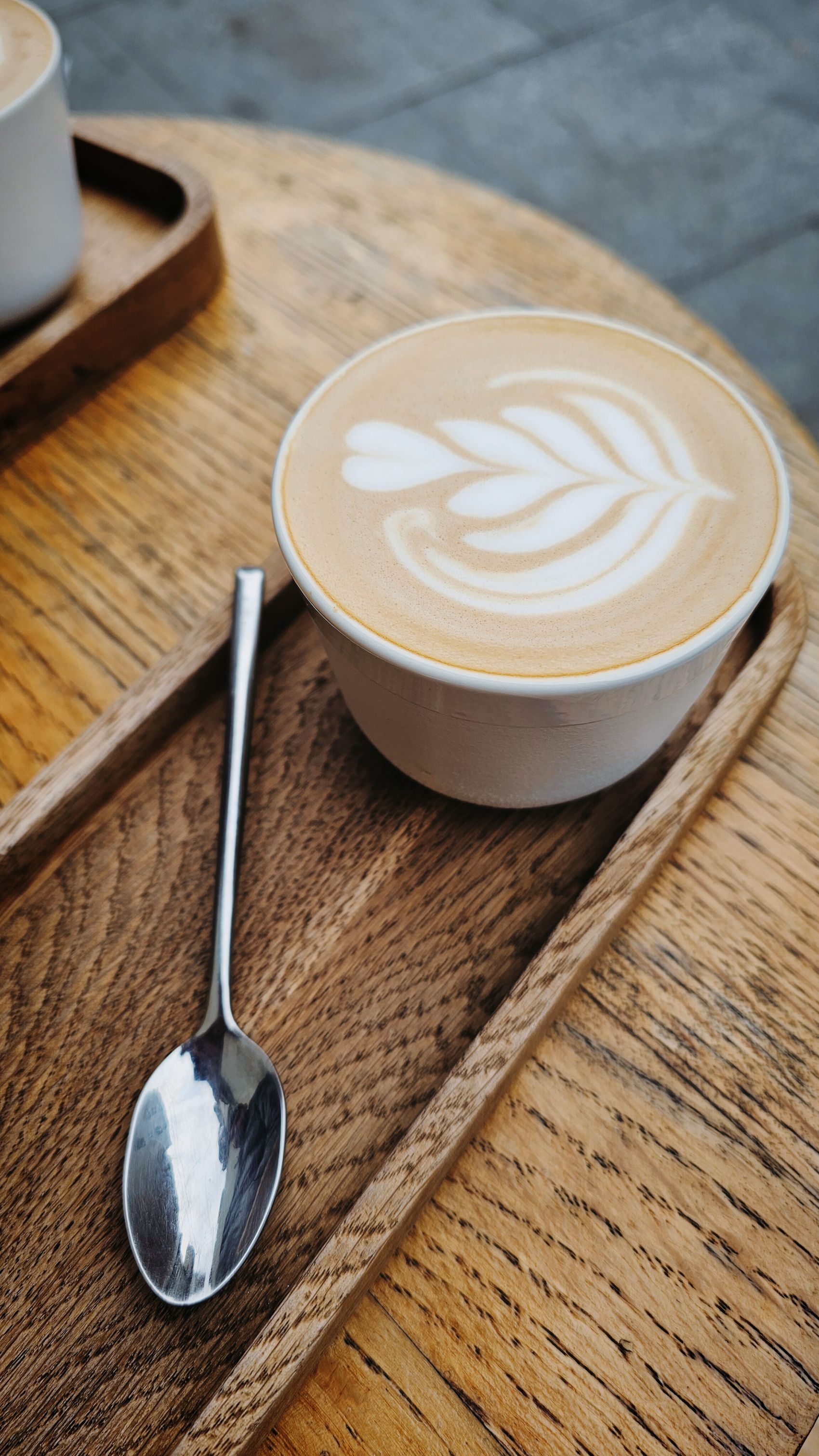 A flat white with latte art on a wooden tray