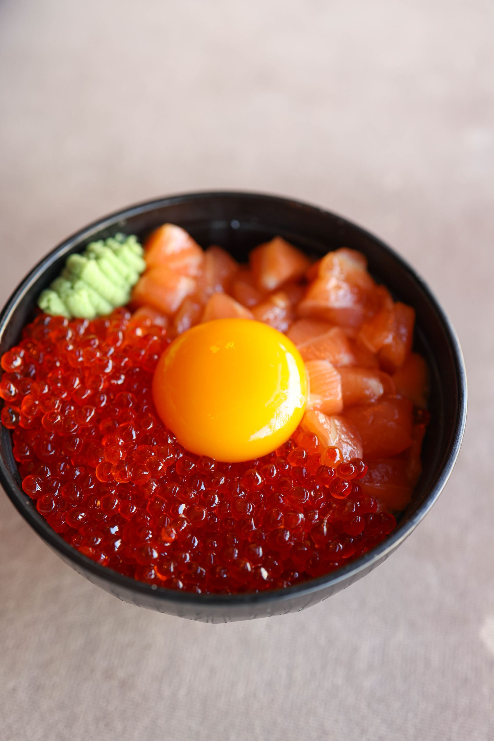 A Japanese-fusion rice bowl topped with salmon, ikura roe and a cured egg yolk